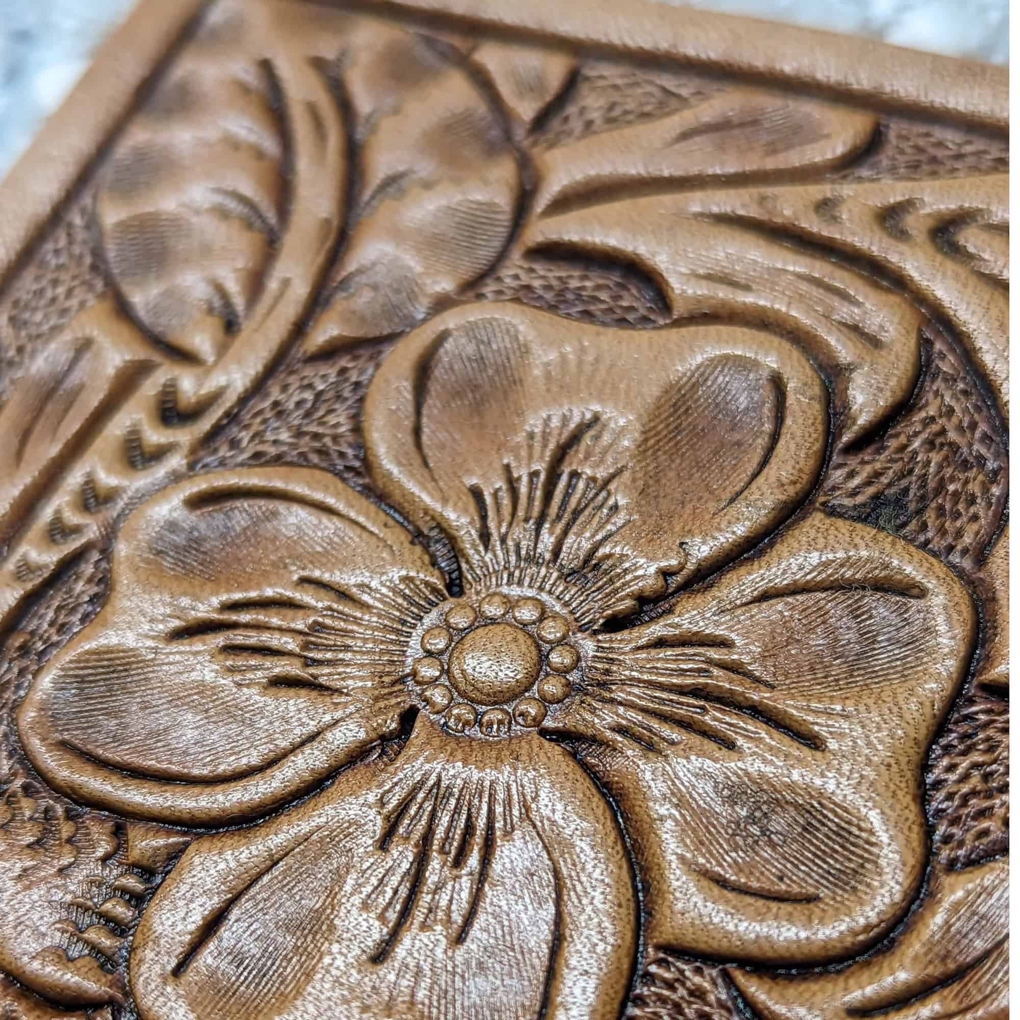 Leather coaster tooled with a flower, vines, and a leaf.