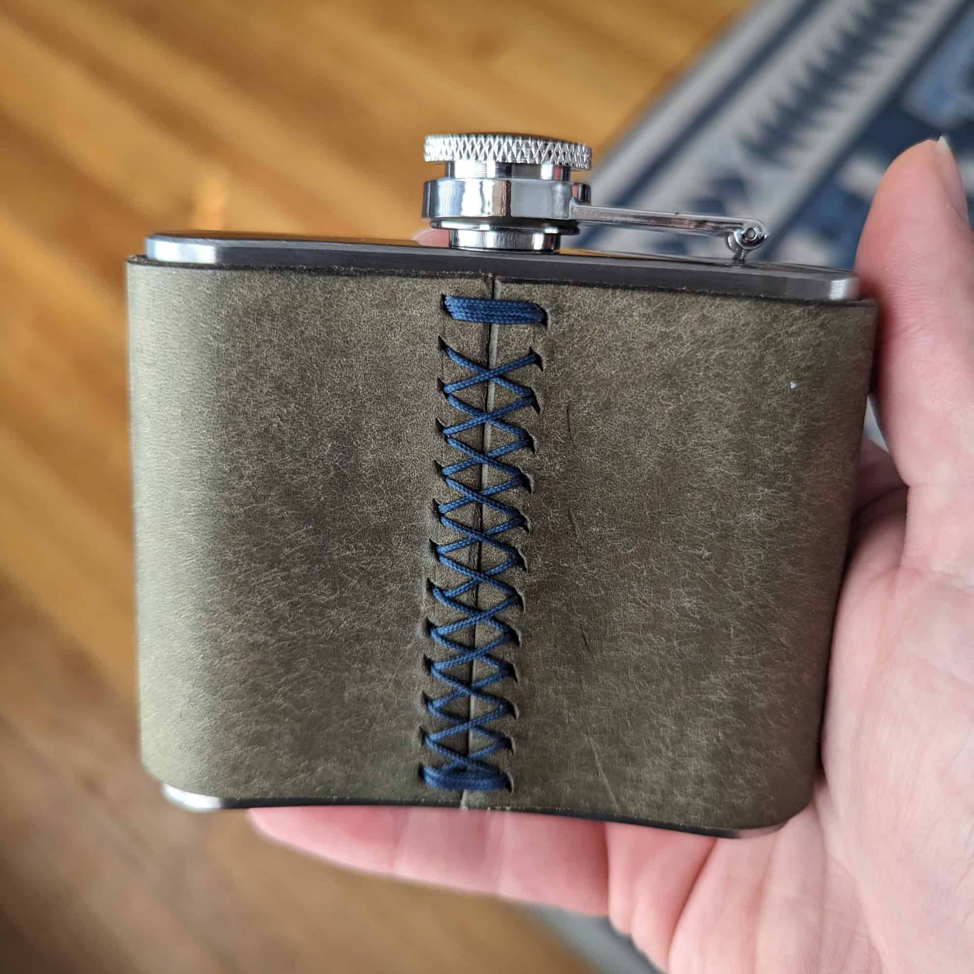 Flask covered in a leather sleave with a baseball stitch.