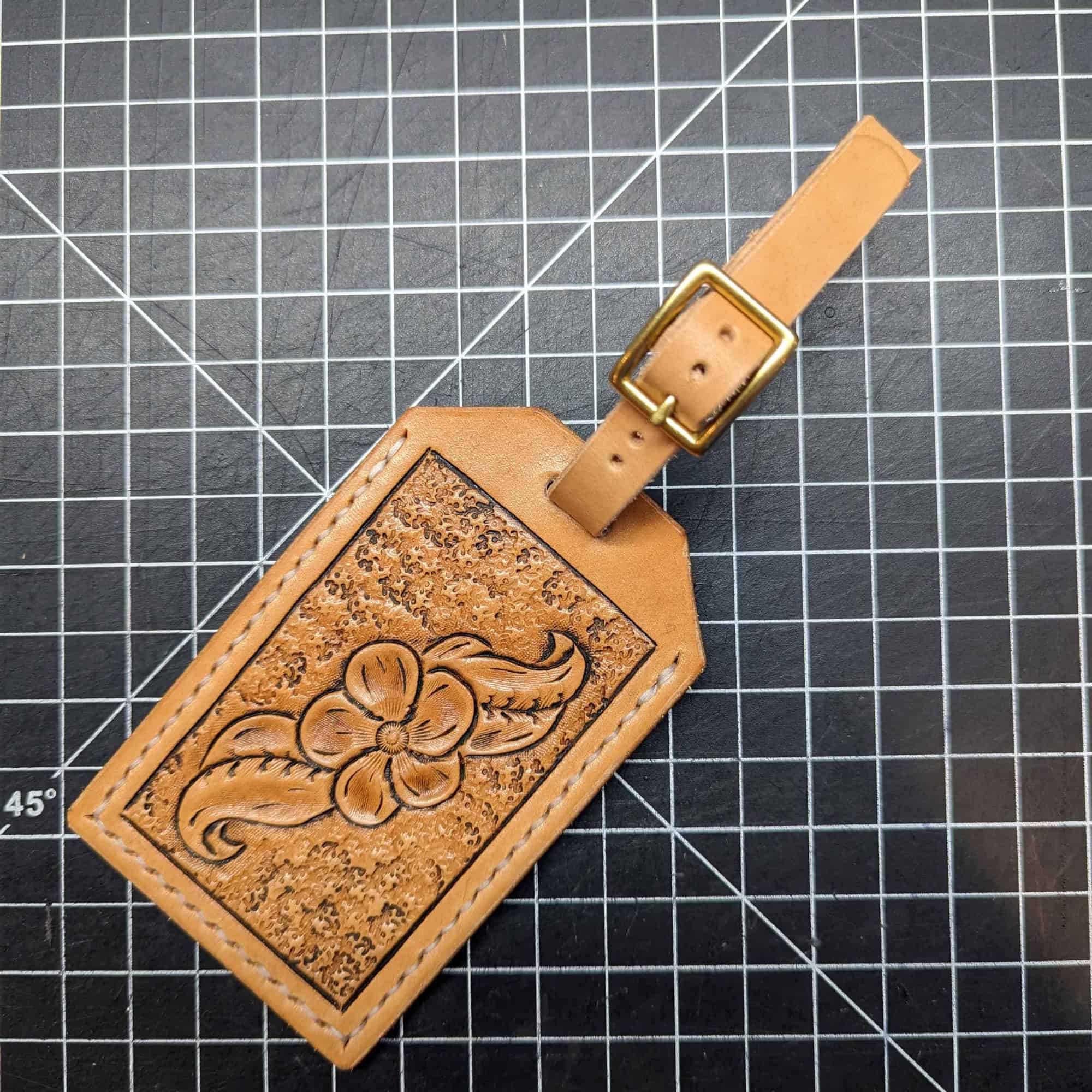 Leather luggage tag tooled with an image of a flower.